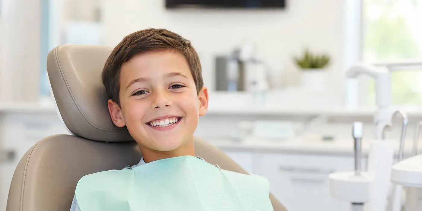 A smiling child sitting in a dental chair after having sealants placed