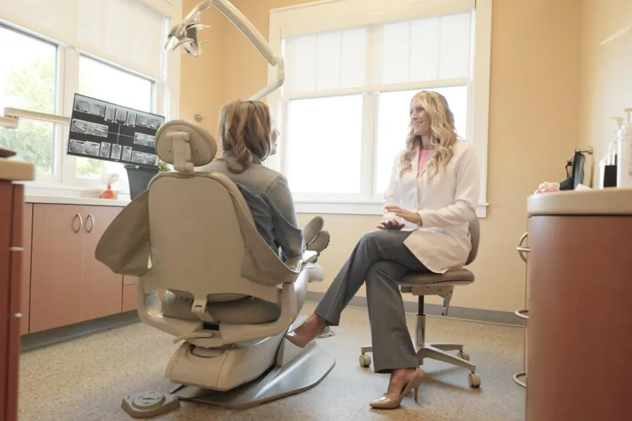 A Grandville Dental clinician speaking with a seated patient in a treatment room